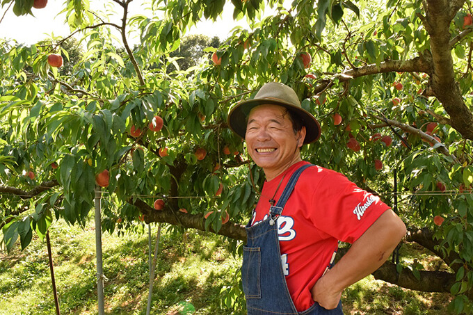 果樹園をバックに笑顔の平田社長